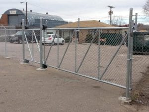 Galvanized chain link cantilever slide gate with diagonal bracing across a commercial lot entrance