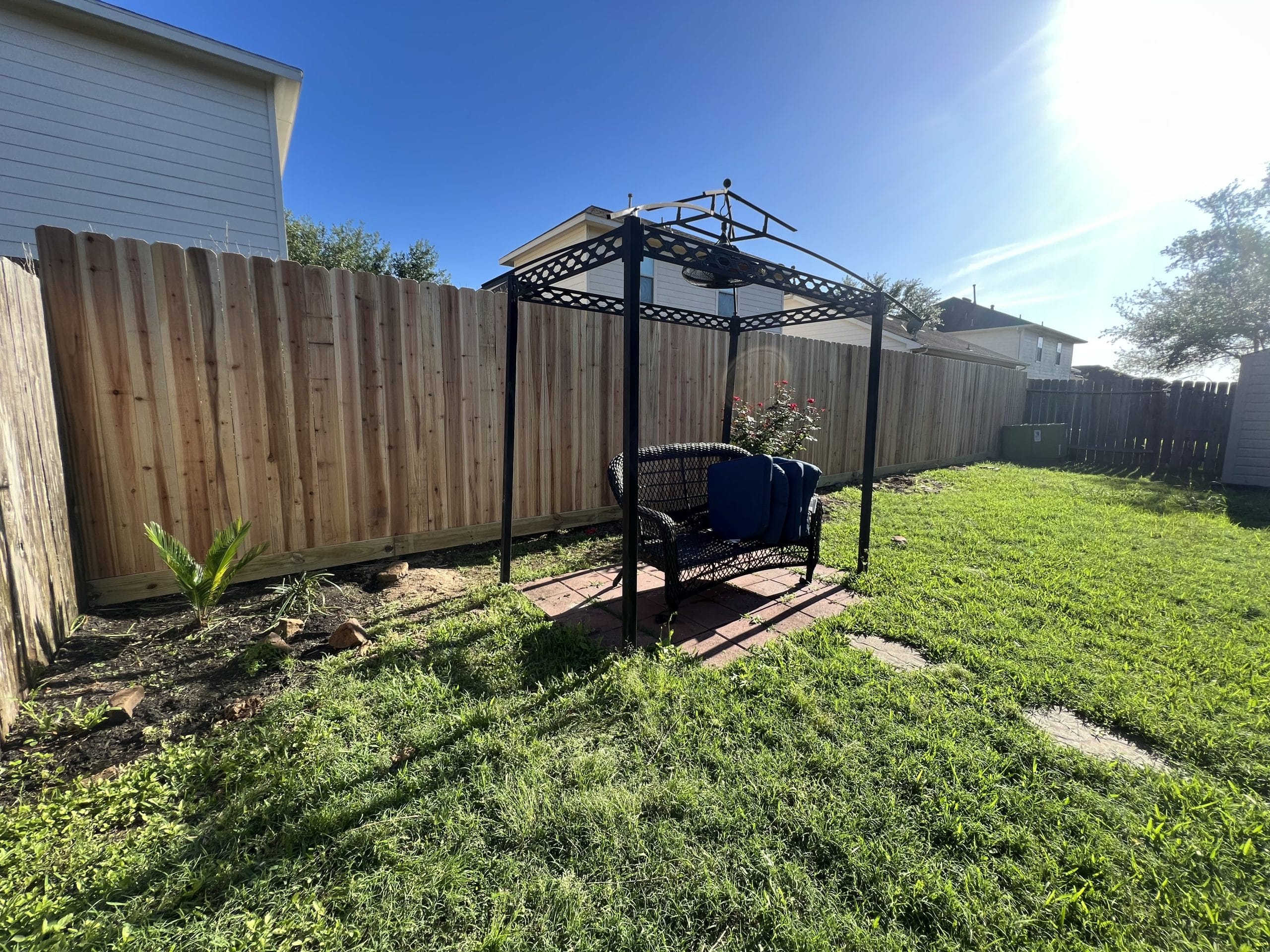 Wood privacy fence along the side of a backyard lawn with a canopy swing in Kemah