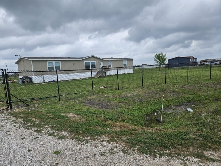Chain link fence enclosing an open lot beside a single-storey building