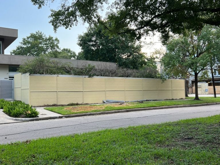 Tall cream-coloured solid panel fence along a residential street