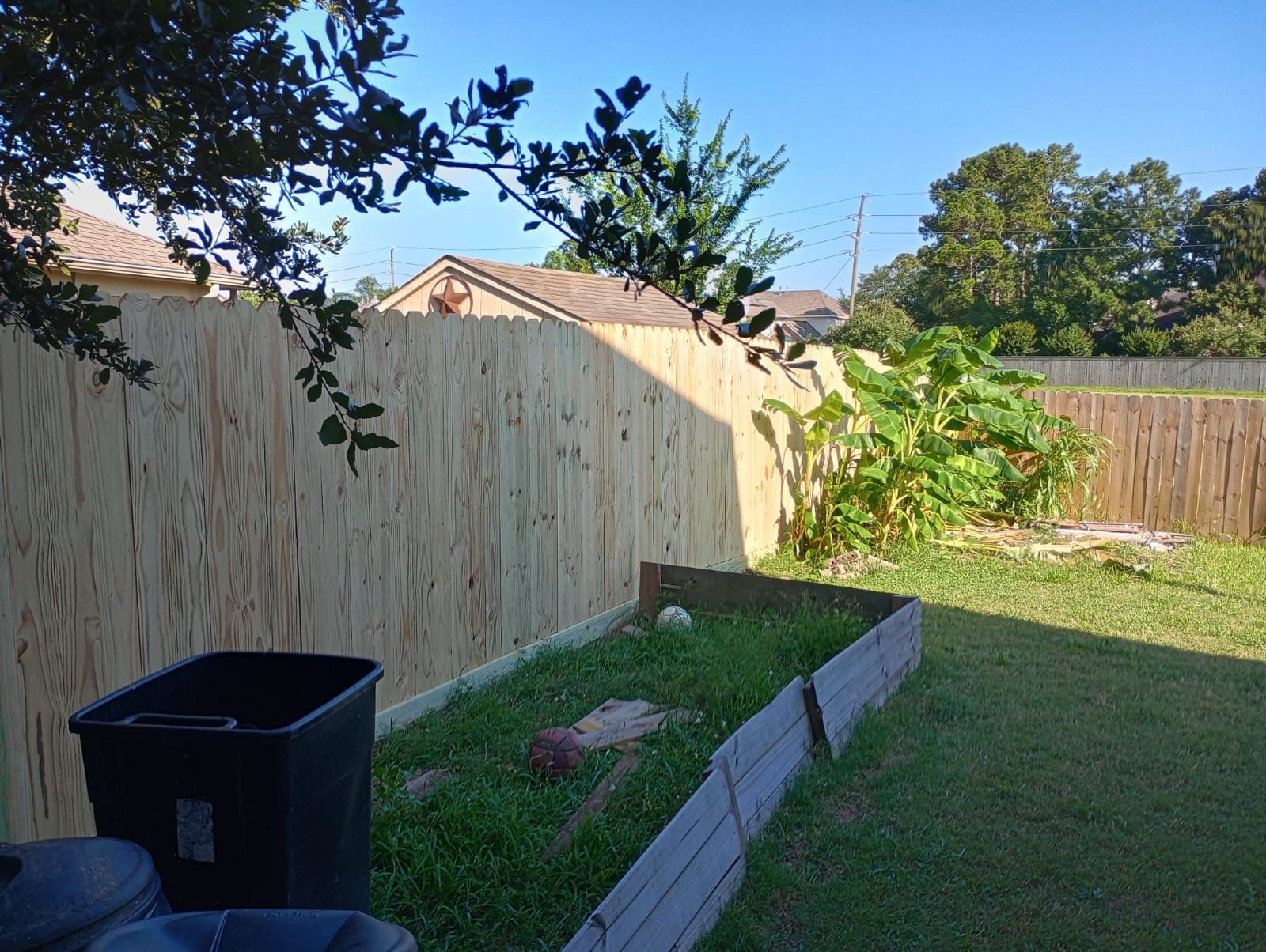 Wood privacy fence around a back garden with shade trees