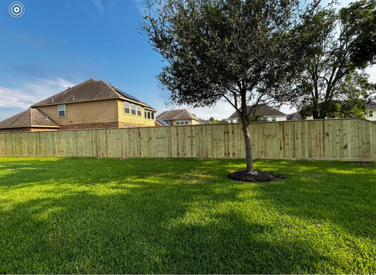 Solid wood privacy fence around a lawn with a young tree