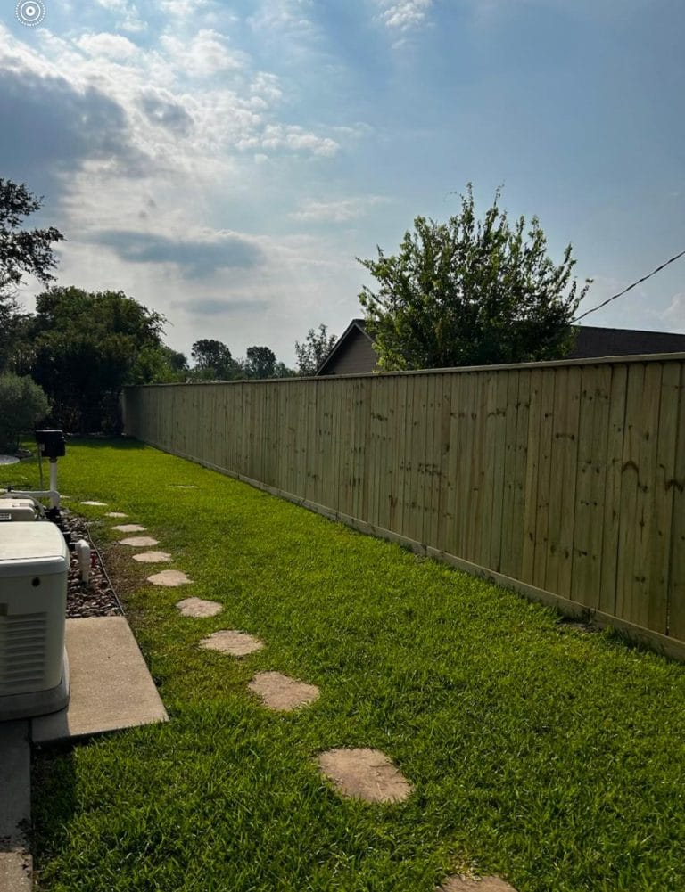 Wood privacy fence beside a lawn with stepping stones