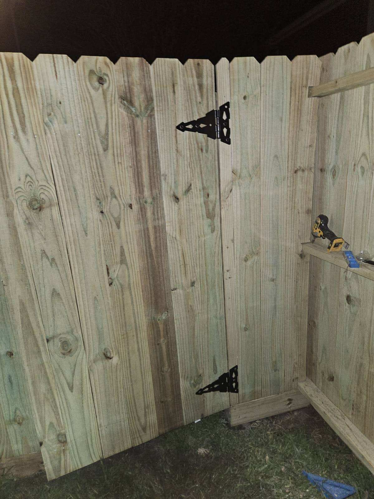 Wood gate with black strap hinges in a fence corner