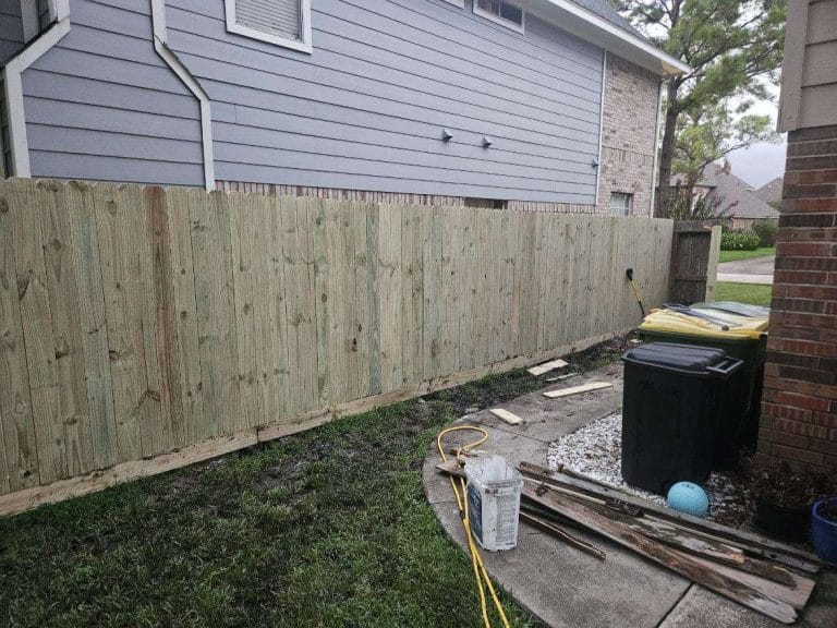 Wood privacy fence under installation beside a house