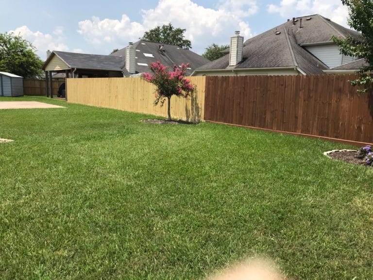 Wood privacy fence enclosing a large lawn behind houses