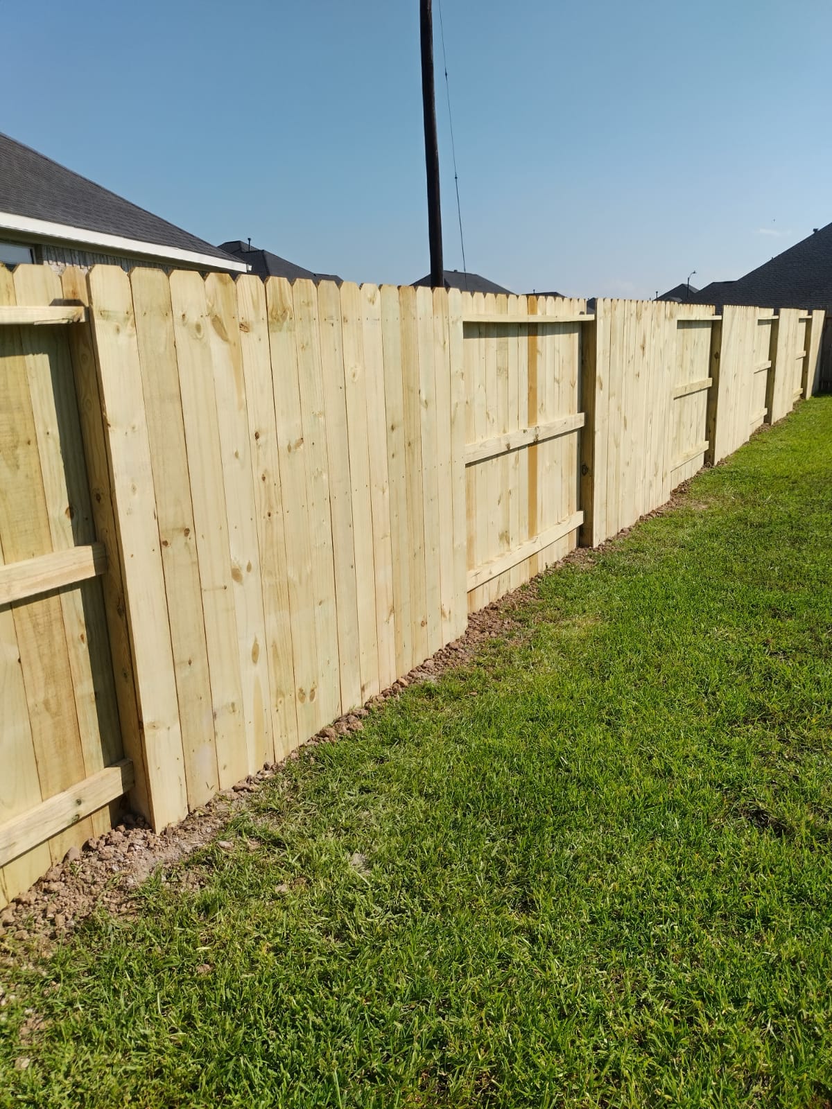 New wood privacy fence running along the edge of a lawn, Galveston, Texas