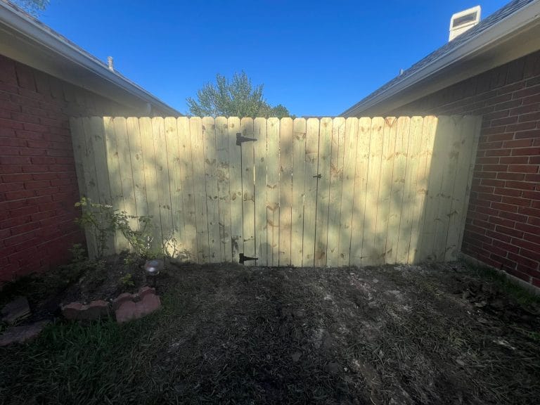 Wood gate fitted between two brick house walls
