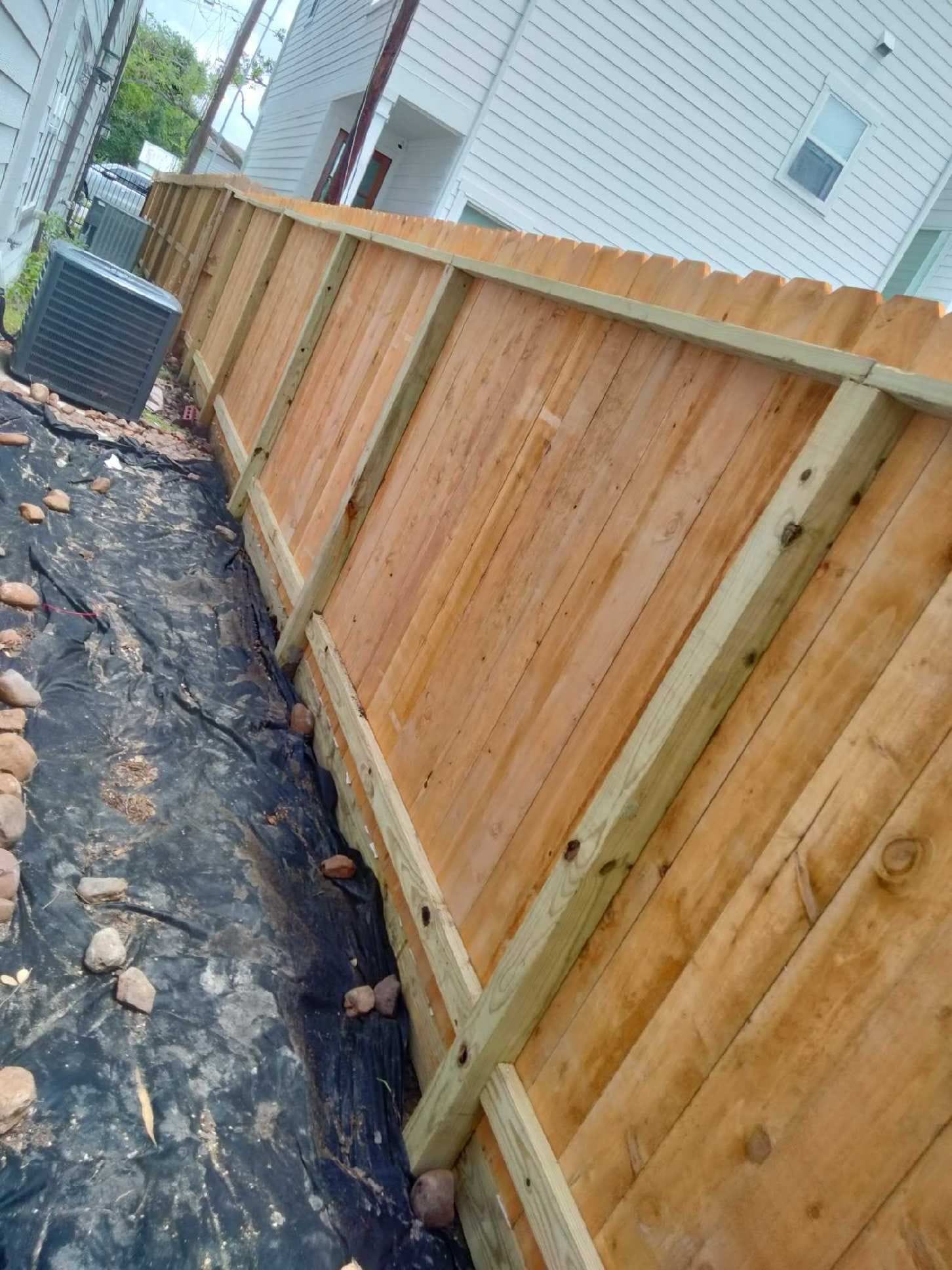 New wood fence beside a stone-lined drainage channel