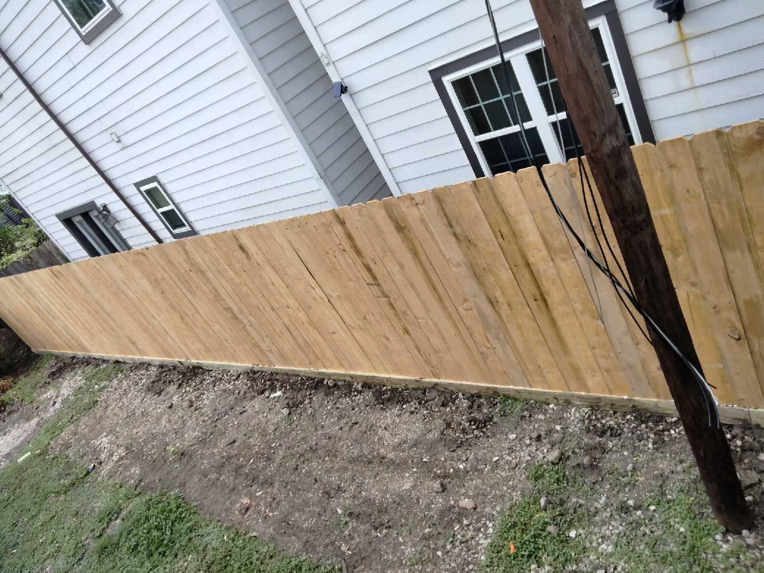 New wood fence running beside a white weatherboard house