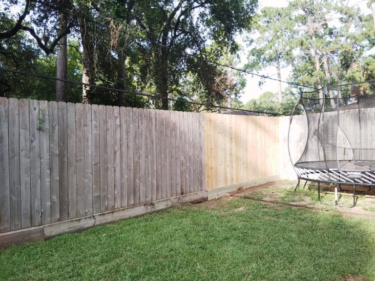 Wood privacy fence enclosing a back garden with a trampoline