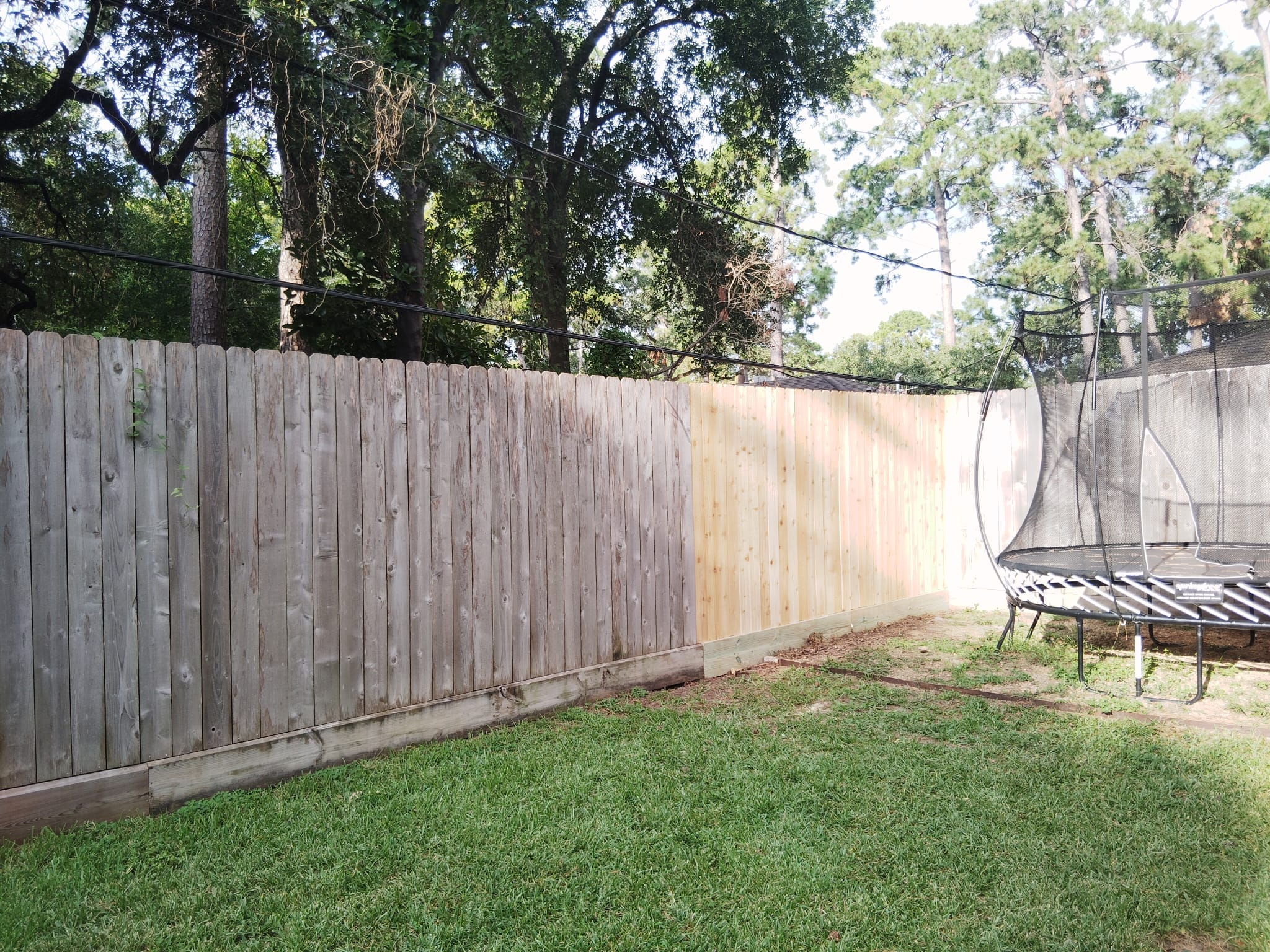 Wood privacy fence enclosing a back garden with a trampoline