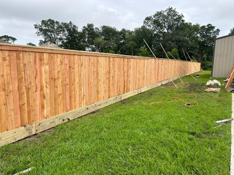 Long new wood privacy fence with temporary bracing during installation on a Galveston job
