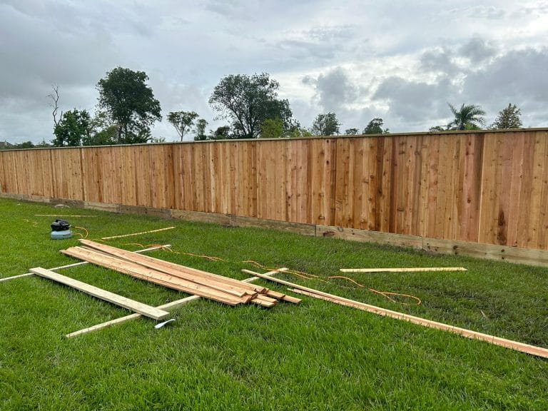 Long wood privacy fence with offcut lumber on the grass