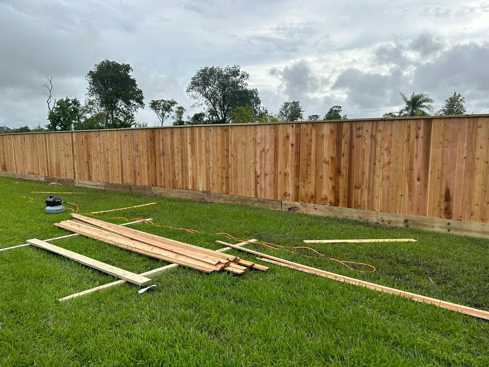 Long wood privacy fence with offcut lumber on the grass