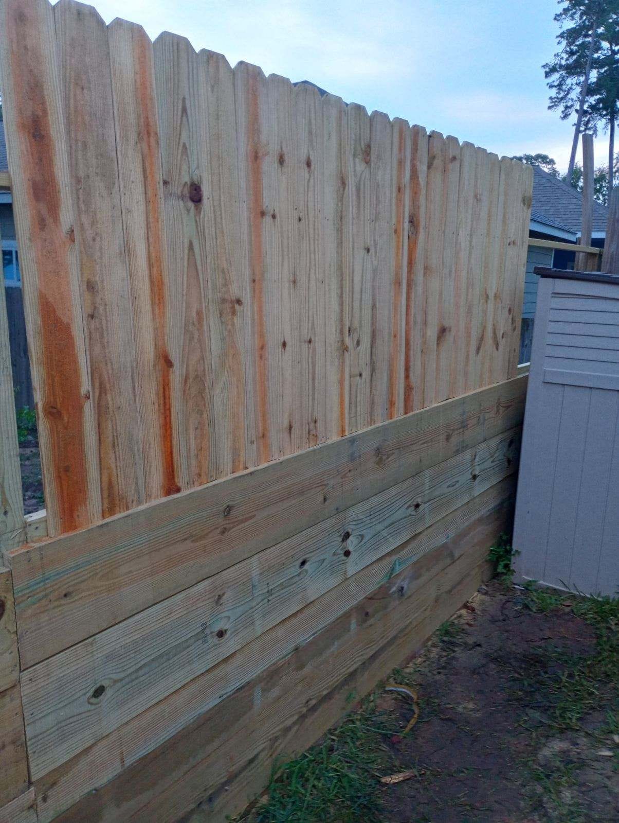 Wood fence with new pickets fitted above older boards