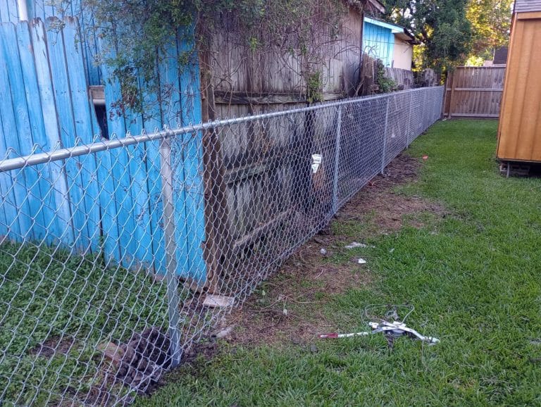 Chain link fence running beside a blue-painted building