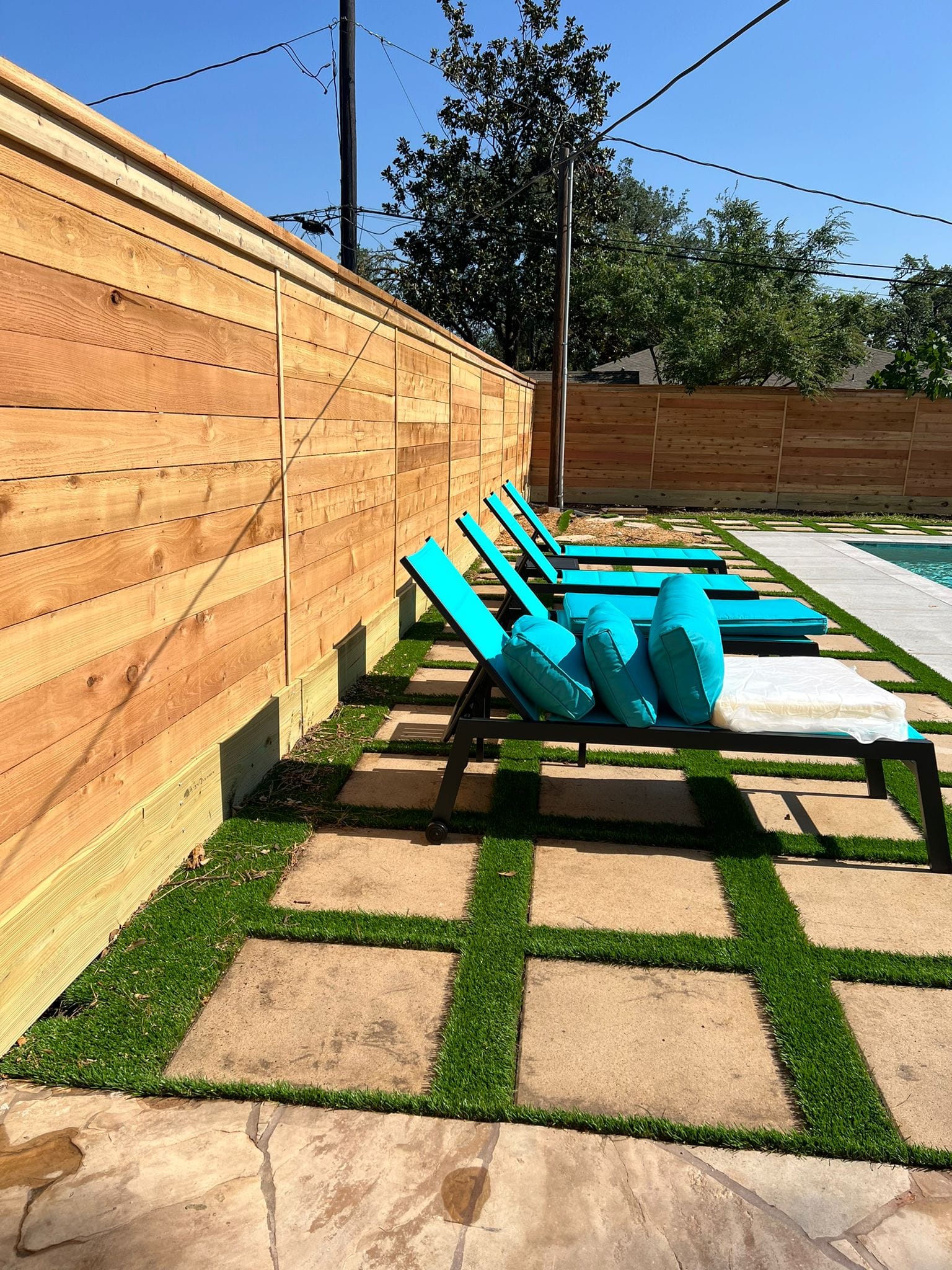 Horizontal cedar privacy fence enclosing a pool patio with loungers
