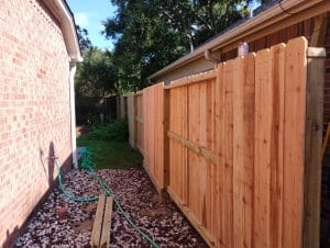 Stained cedar fence and gate running beside a brick house