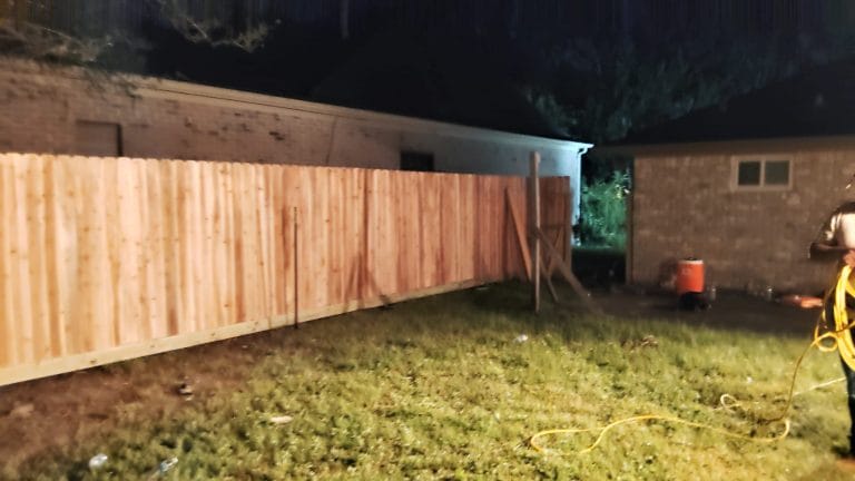 New wood privacy fence photographed at dusk during installation