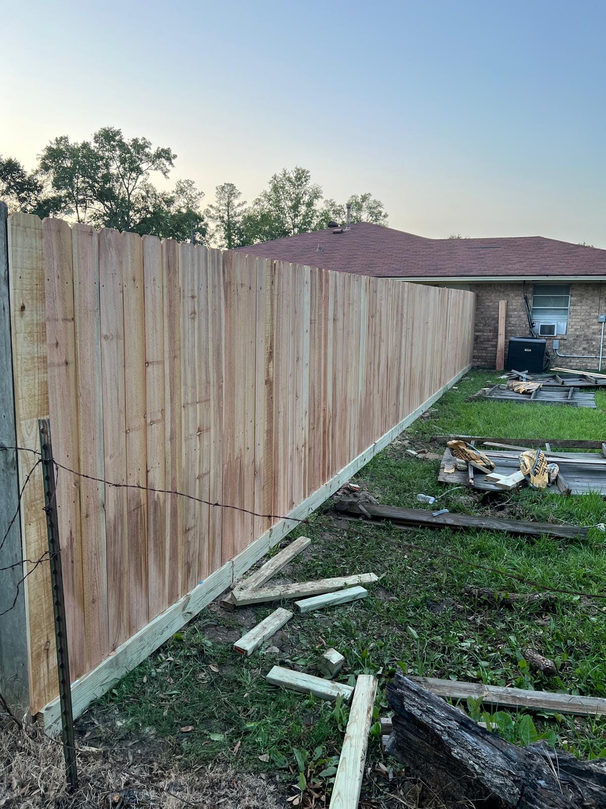 Cedar fence at dusk with offcuts on the ground during installation