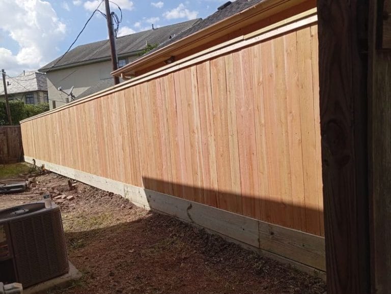 New cedar privacy fence running along a cleared yard edge