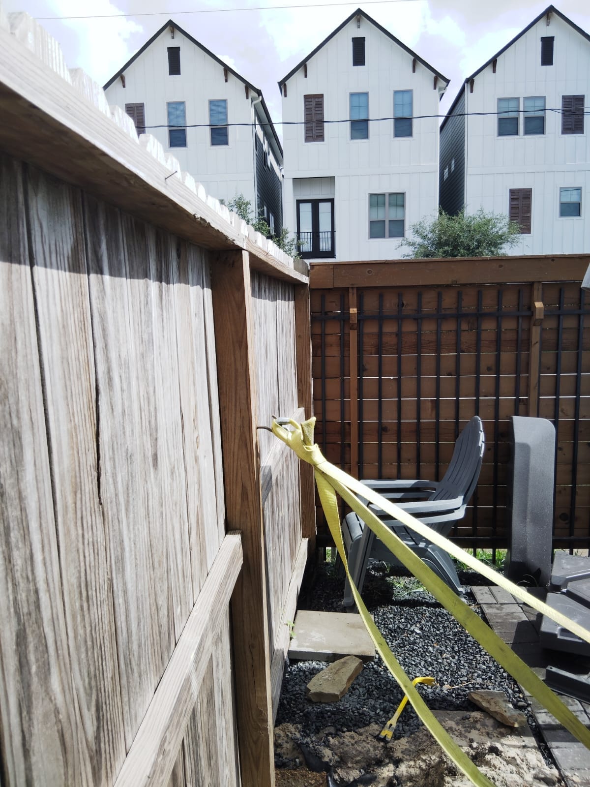 Wood fence meeting a black metal fence beside townhouses