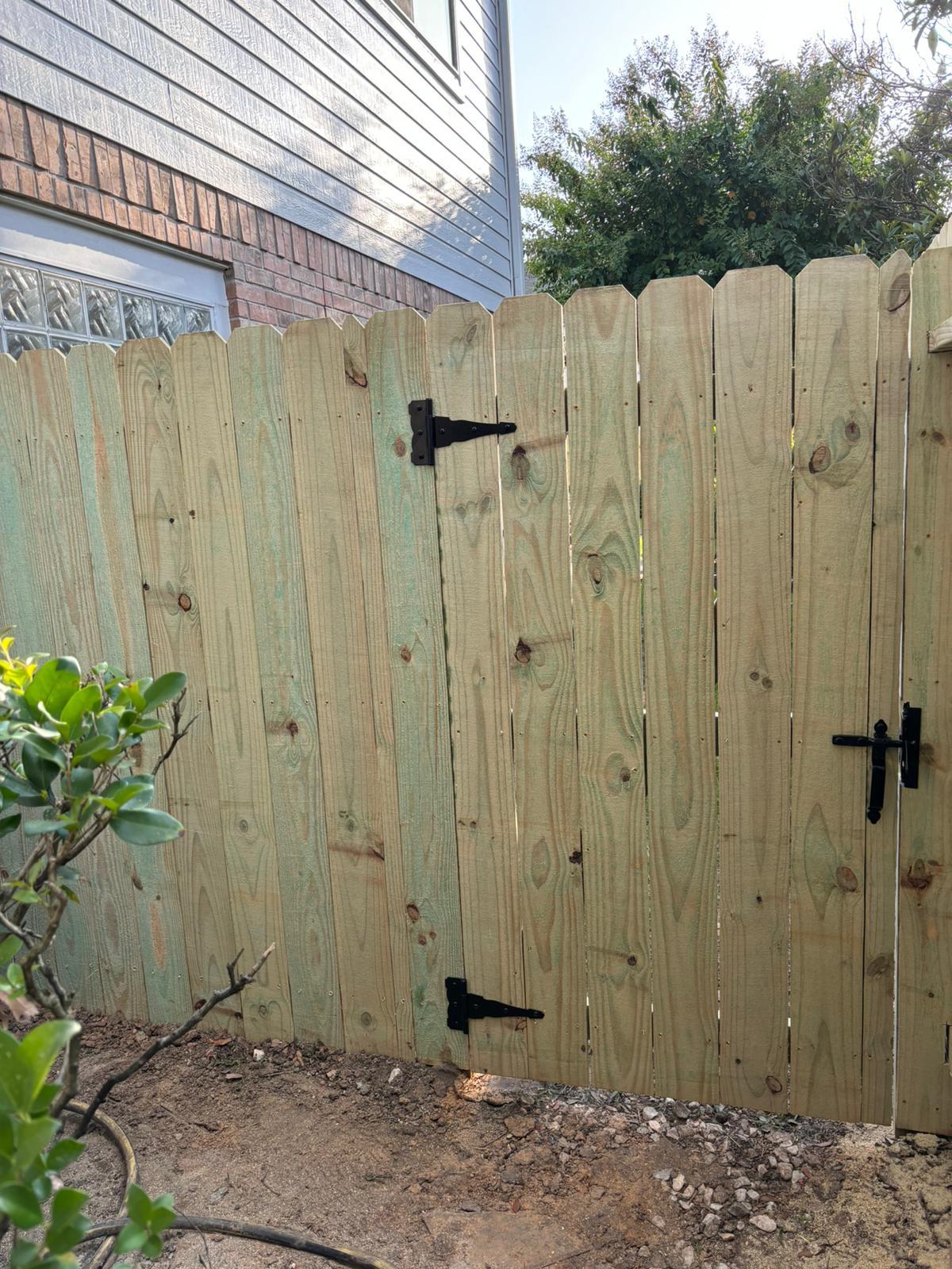 New pine gate with black strap hinges at a brick house in Rosharon