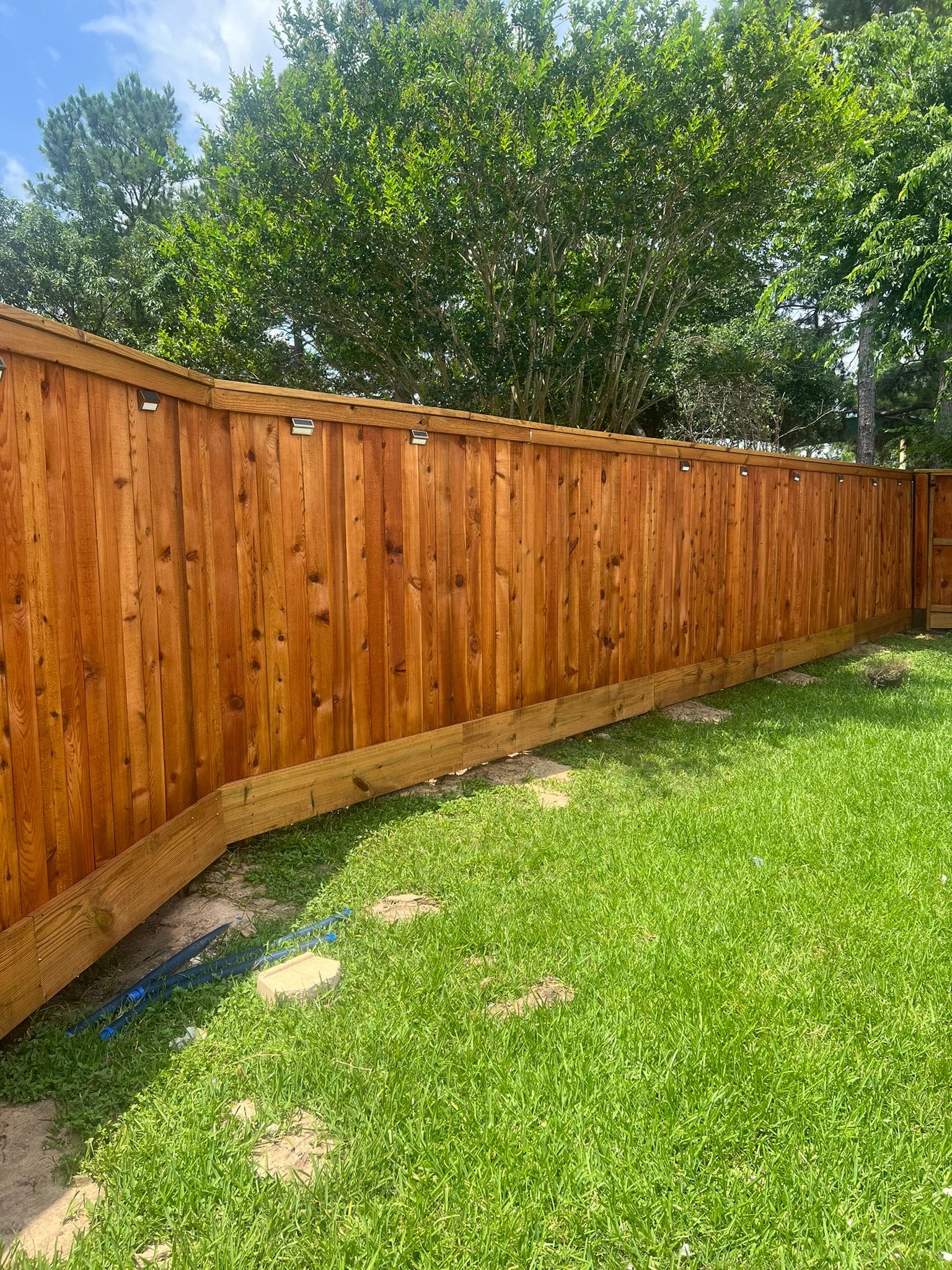 Wood privacy fence around a back lawn with shade trees
