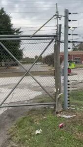 Galvanised chain link fence with barbed wire beside utility poles