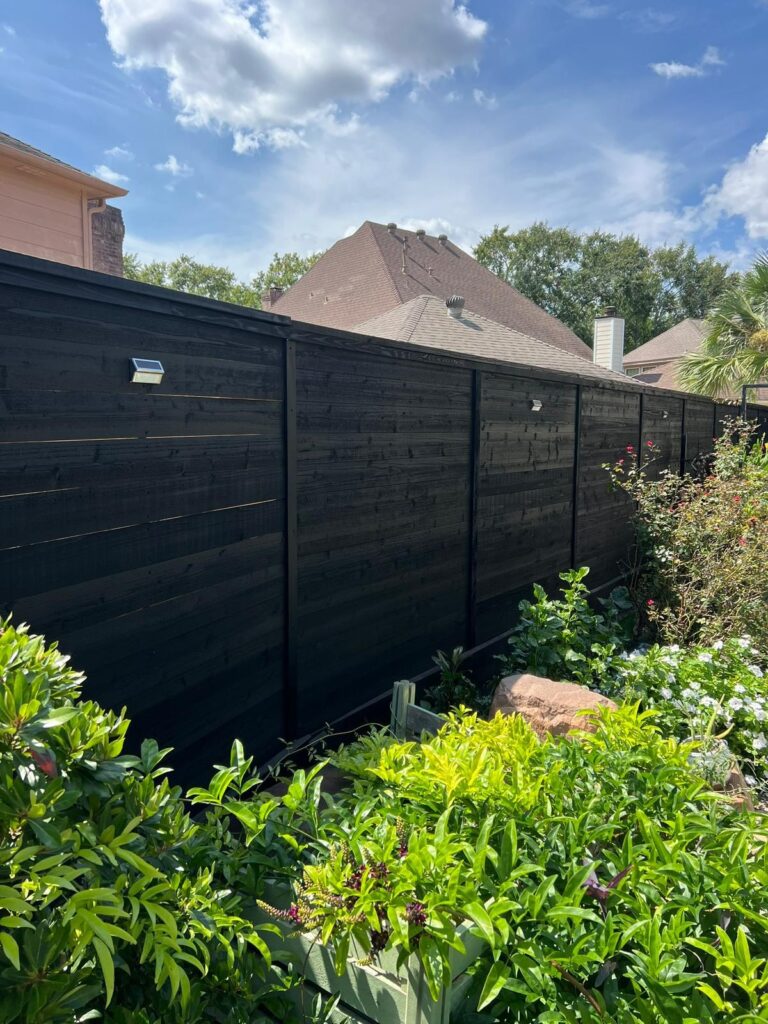 Modern black horizontal-style privacy fence in a garden setting