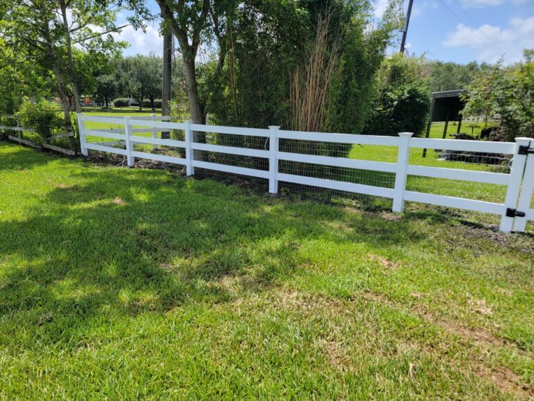 White vinyl three-rail ranch fence along a grassy yard boundary