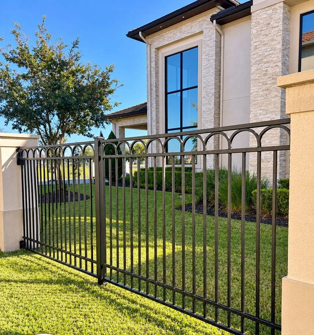 Arched-top iron walk gate beside a stone wall