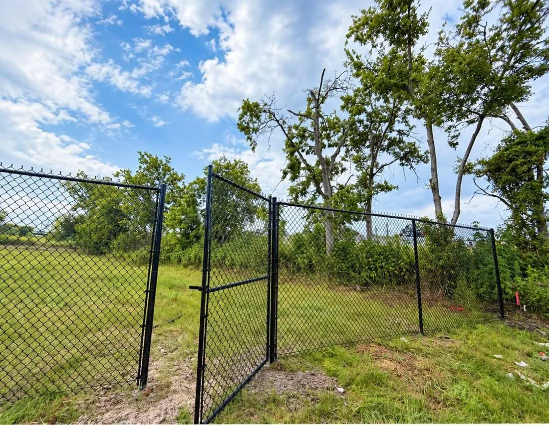 Black chain link walk gate in a green lot
