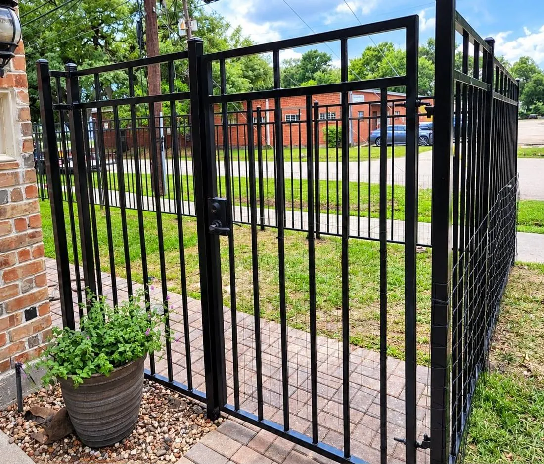 Black iron walk gate beside a brick wall