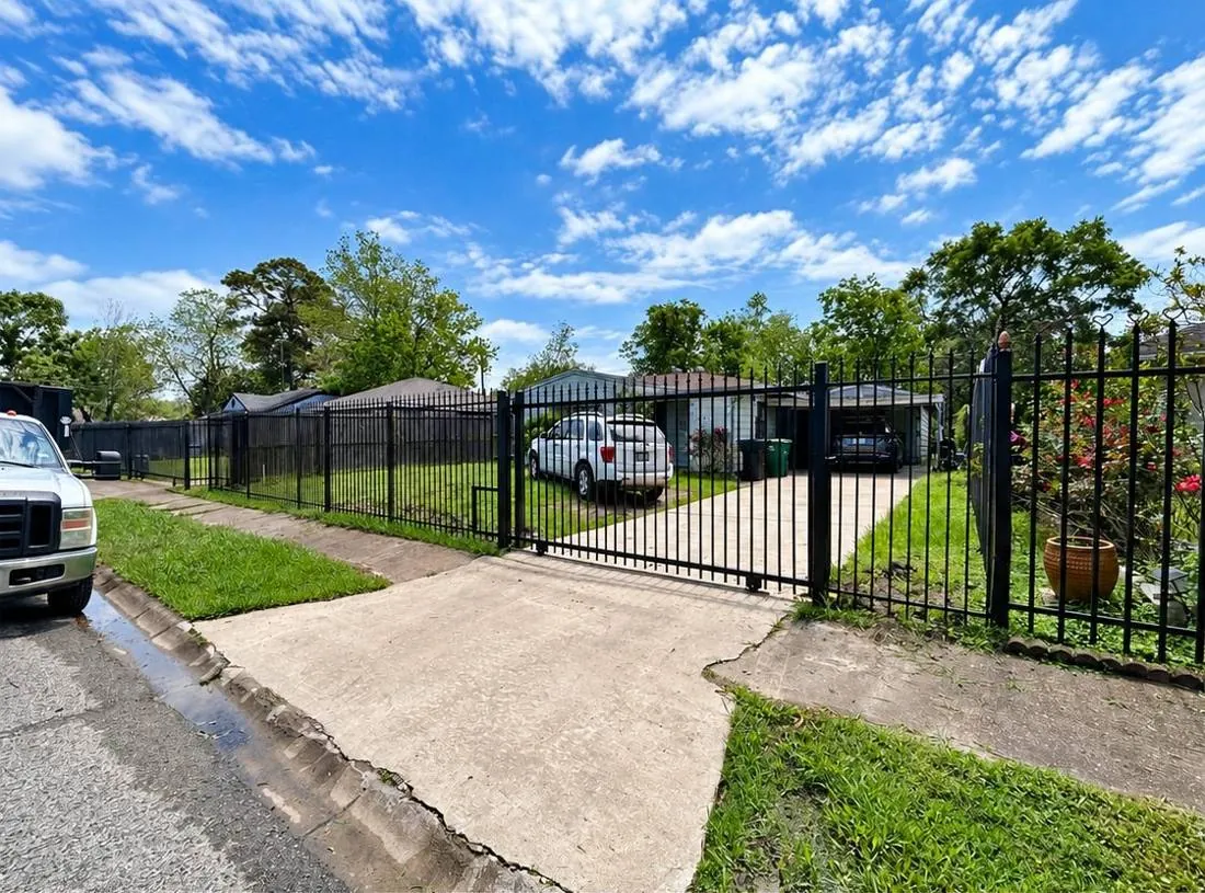 Black ornamental fence and driveway gate along a front yard
