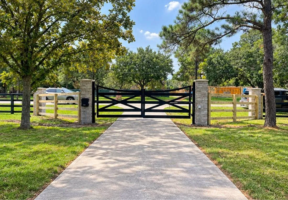 Black ranch-style X-brace gate with stone posts