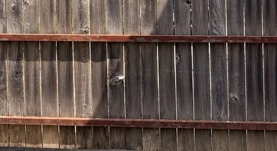 Before: weathered gray wood fence and gate at the same driveway