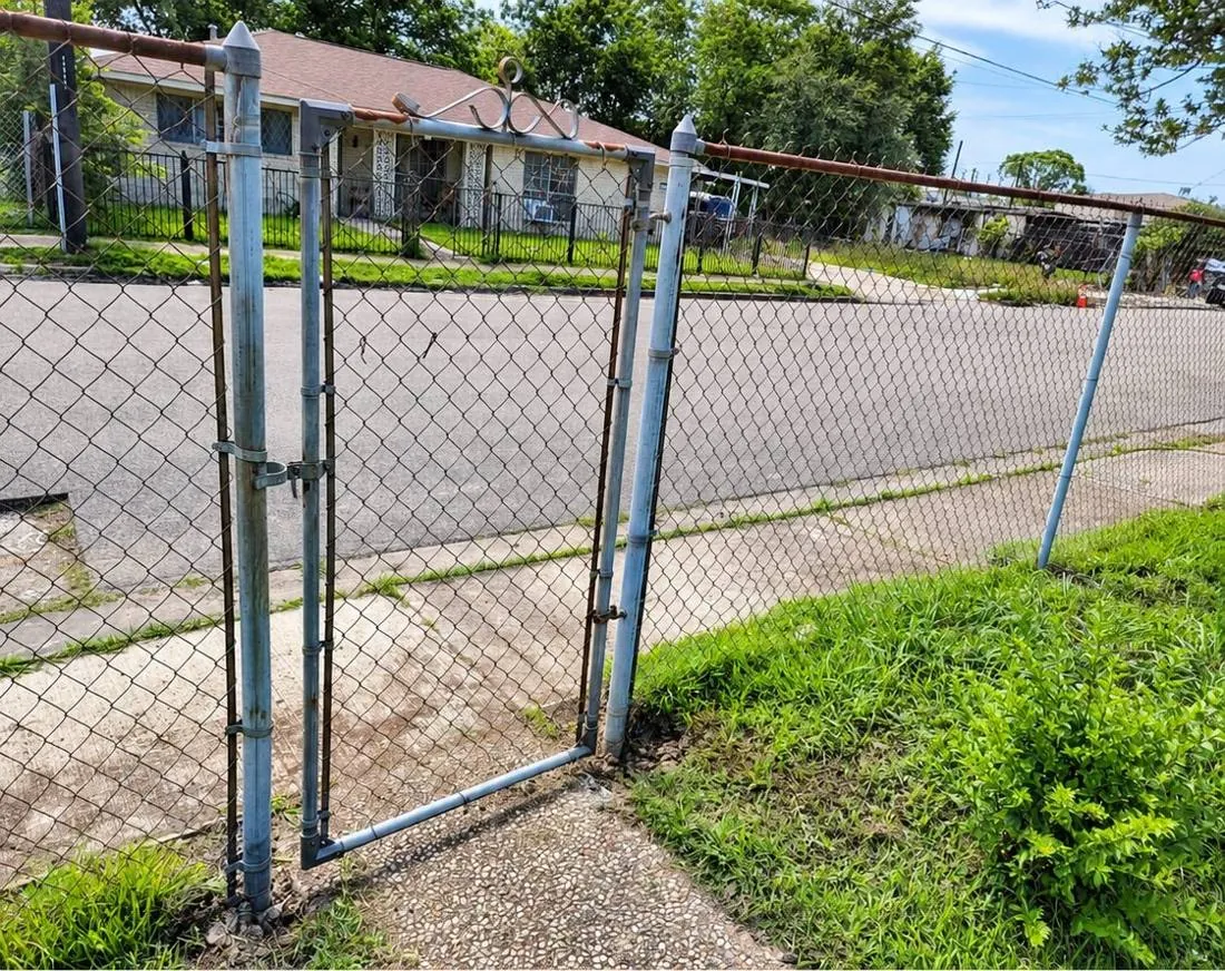 Galvanized chain link walk gate by a sidewalk